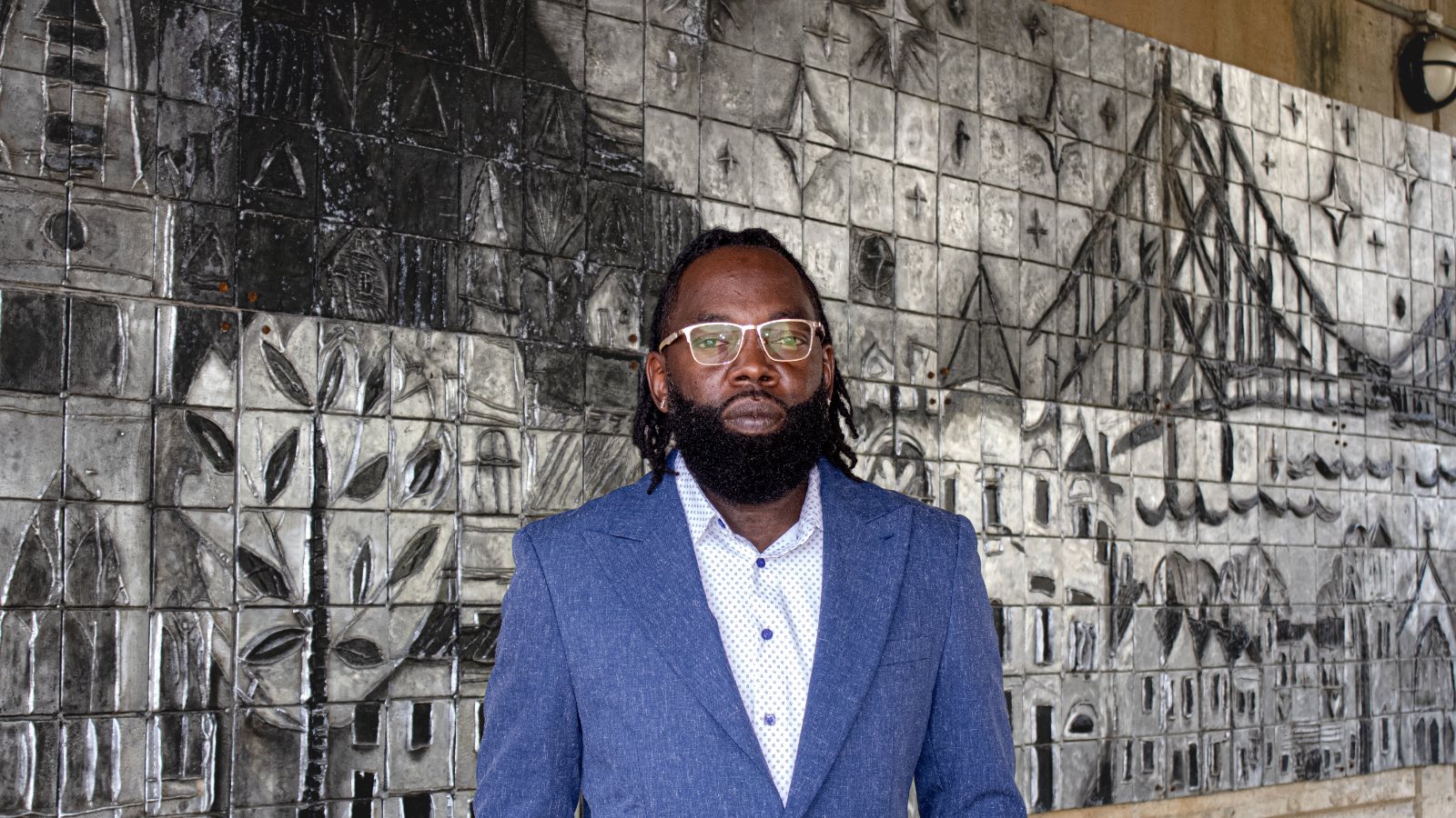 LaRon Washington in front of a tile mural of Maysville's riverfront and suspension bridge
